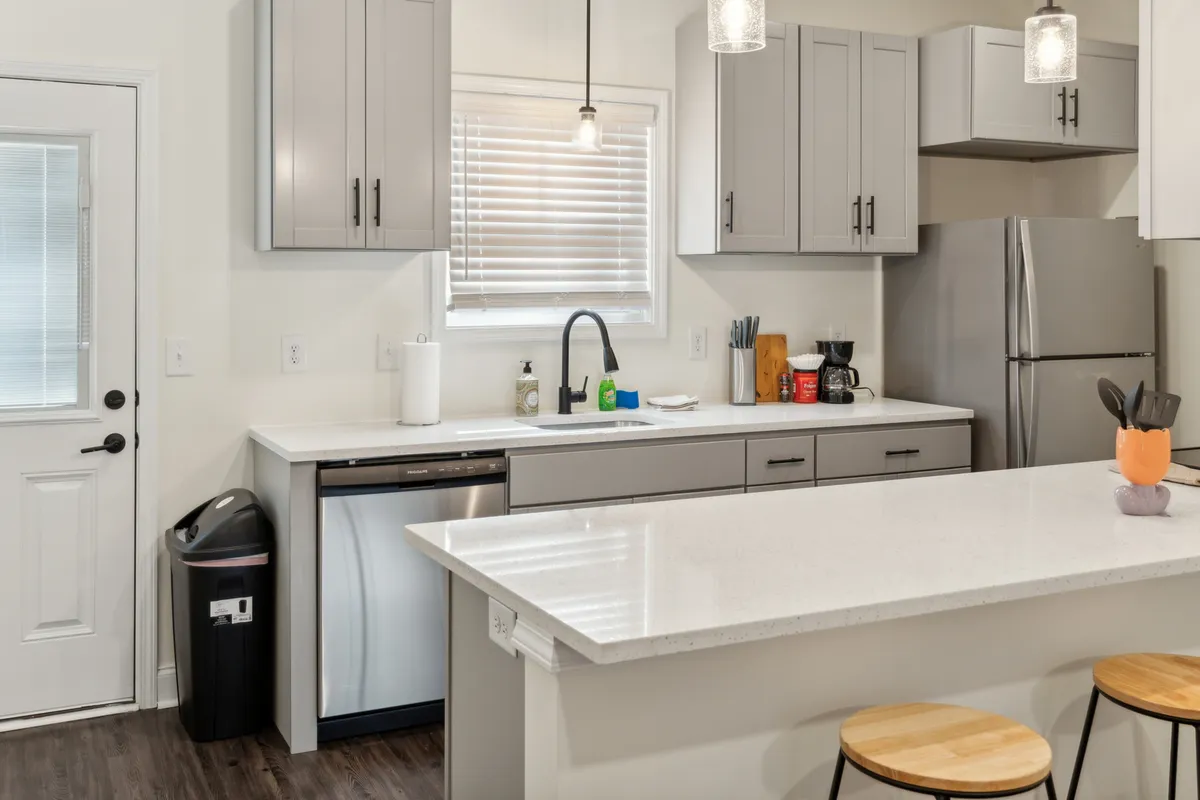 A spacious and modern kitchen with a central island, sleek appliances, ample cabinetry, and a large window filling the space with natural light. The island provides room for meal prep and casual conversations, while the open layout encourages easy movement and socializing.